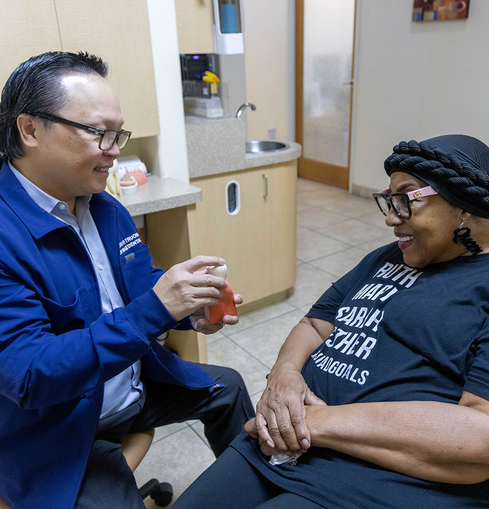 Dr. Truong. showing a patient a model of dental implants